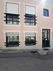 a pink building with black windows and a door at Casa Dos Arcos in Aveiro +14 photos