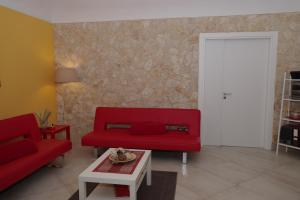 sala de estar con sofá rojo y mesa en La Nicchia, en Noto