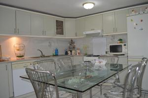 a kitchen with white cabinets and a glass table and chairs at VILA SS KEKEZI in Gjirokastër
