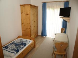 a bedroom with a bed and a chair and a window at Frühstückspension Kärntnerhof in Malta