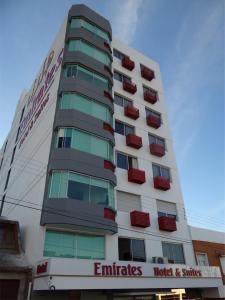 a tall white building with red windows at Emirates Hotel & Suites in Santana do Livramento