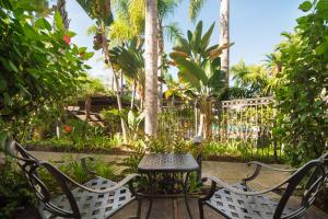a table and chairs in a garden with palm trees at Humphreys Half Moon Inn in San Diego