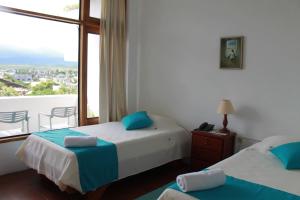 a hotel room with two beds and a balcony at Posada del Mar in Puerto Ayora