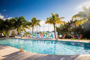 a large swimming pool with chairs and palm trees at True Blue Bay Resort in Saint Georgeʼs