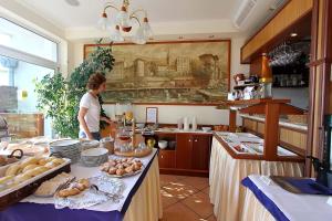a woman standing in a kitchen with a table with food at Hotel Stanger in Lovran