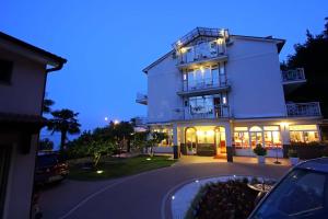 a white building with a car parked in front of it at Hotel Stanger in Lovran