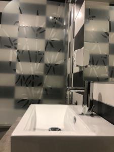 uma casa de banho com um lavatório branco e um espelho. em Hôtel L'ange de la vallée em Oyonnax