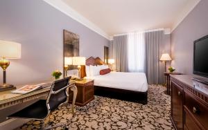 ロサンゼルスにあるThe Biltmore Los Angelesのベッドと机とテレビがあるホテルの部屋