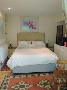 a bedroom with a large bed with white sheets at Sunny Patch in Stroud