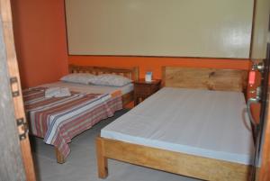 2 camas en una habitación pequeña con paredes de color naranja en Banaue Homestay en Banaue