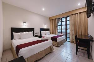 um quarto de hotel com duas camas e uma secretária em Hotel Colonial de Merida em Mérida