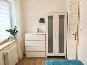 a bedroom with a white dresser and a cabinet at Apartament NOTI Gdynia z parkingiem in Gdynia