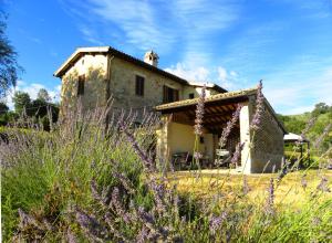 a stone house in a field with purple flowers at Appartamenti Verde Collina Umbra in Bevagna