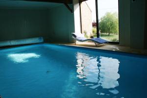 a swimming pool with a chair and a window at Herbages de Beauvais in Orgères-la-Roche
