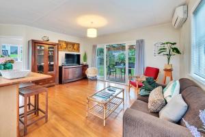 uma sala de estar com um sofá e uma mesa em Sunny & Cozy Home near Western Springs em Auckland