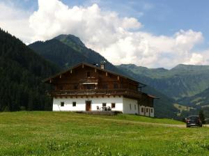 ein Haus auf einem Hügel mit Bergen im Hintergrund in der Unterkunft Alpenbauernhaus Vorderbrandthof in Saalbach-Hinterglemm