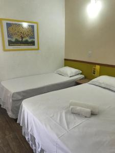 two beds in a hotel room with a picture on the wall at QUINZE HOTEL & POUSADA in Bataguaçu