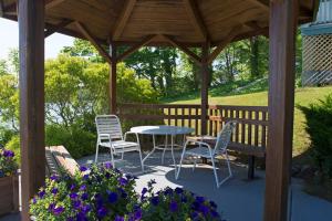 a wooden gazebo with a table and chairs and flowers at The Cove Motel in Orleans