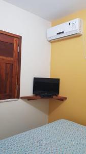 um quarto com uma cama e uma televisão na parede em Pousada Barra Sol em Barra Grande