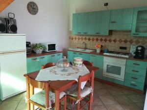 a kitchen with green cabinets and a table with chairs at CALLIMACO'S HOME Comfort e Deluxe in Capaccio-Paestum