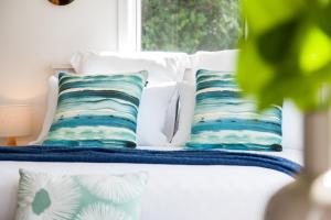 een bed met vier kussens en een raam bij Seaview Studio in Ohope Beach