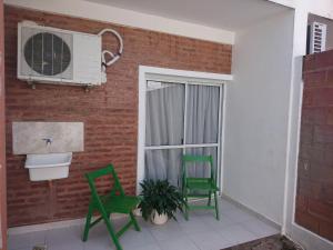 a balcony with two green chairs and a window at DEPARTAMENTO TEMPORARIO DONOVAN in Resistencia