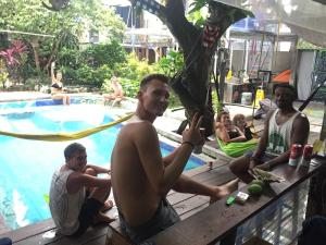 a group of men sitting on a table by a swimming pool at Yez Yez Yez All Good Hostel in Yogyakarta