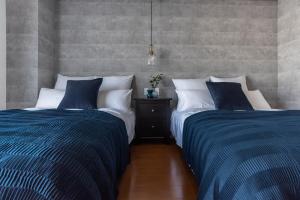 two beds sitting next to each other in a bedroom at Villa Penthouse Tenma in Osaka