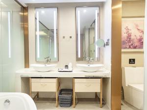 a bathroom with two sinks and two mirrors at Lavande Hotel (Yongxin Bubugao Times Square) in Yongxin