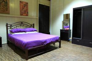 a bedroom with a bed with purple sheets on it at Muntri House in George Town