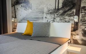 a bed with a yellow pillow and a painting on the wall at Home in Dahme
