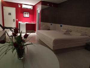 a bedroom with a bed and a table with a vase of flowers at VEGAS MOTEL in Imperatriz