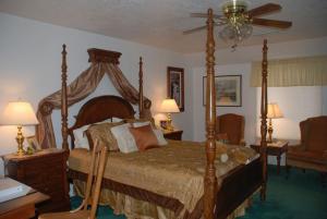 a bedroom with a canopy bed with two lamps and a chair at Novel House Inn at Zion in Springdale