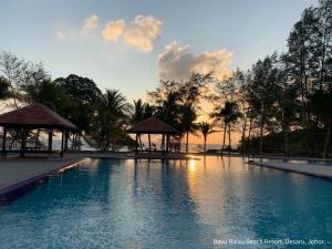 a swimming pool with a gazebo and a sunset at Desaru, Bayu Balau Beach Resort in Desaru