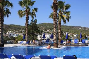 a woman in the swimming pool at a resort with palm trees at Hotel Blue Fountain in Agia Marina Aegina