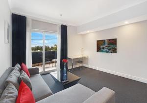 sala de estar con sofá y ventana en Sydney Airport Suites, en Sídney