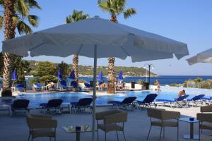 a large white umbrella next to a swimming pool at Hotel Blue Fountain in Agia Marina Aegina