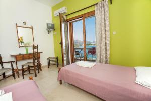 a bedroom with a bed and a desk and a window at Melas Apartments in Agios Nikolaos