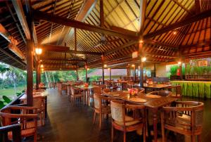 un restaurante con mesas y sillas de madera. en Cempaka Belimbing Villa, en Blimbing