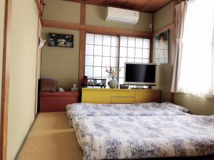 Schlafzimmer mit einem Bett und einem Flachbild-TV in der Unterkunft Takeuchi Goya in Chiba