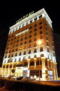 a lit up building with cars parked in front of it at Tariq Almoayed Tower in Manama