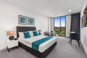 a hotel room with a large bed and a large window at Essence Suites Taringa in Brisbane