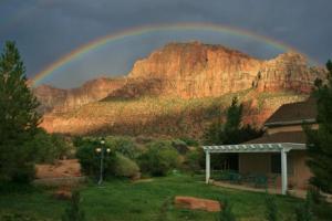 einen Regenbogen über einem Haus vor einem Berg in der Unterkunft Novel House Inn at Zion in Springdale