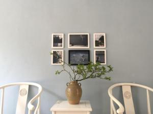 um vaso numa mesa com três fotografias na parede em Zen Box House em Yangshuo