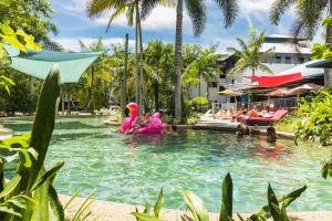 ケアンズにあるSummer House Backpackers Cairnsのピンクの衣装を着た人、プールでリゾートの人