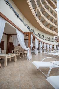 a room with white chairs and tables and curtains at Rhodos Horizon Blu-Adults Only in Rhodes Town
