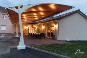 a pergola over a patio with a table at Hôtel Azur Saint Junien Cit'Hotel in Saint-Junien