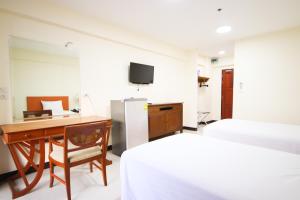 1 dormitorio con 2 camas, escritorio y TV en White House Bizotel, en Bangkok