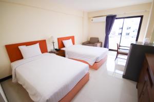 a hotel room with two beds and a window at White House Bizotel in Bangkok