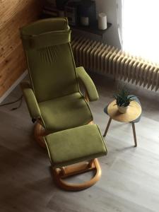 una silla verde sentada en una sala de estar junto a una mesa en Haus Nicole, en Herrischried